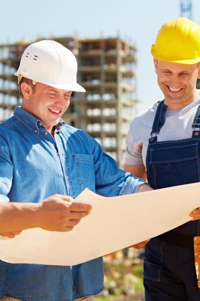 Alta title survey map review on site - ALTA SURVEY Miami Construction professionals reviewing land survey plans on site to ensure alignment for an ALTA title survey.