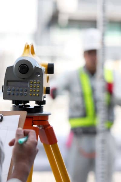Professional land surveyor measuring property lines - ALTA SURVEY Miami Licensed land surveyor using total station equipment to measure and re-establish property boundaries after a flood