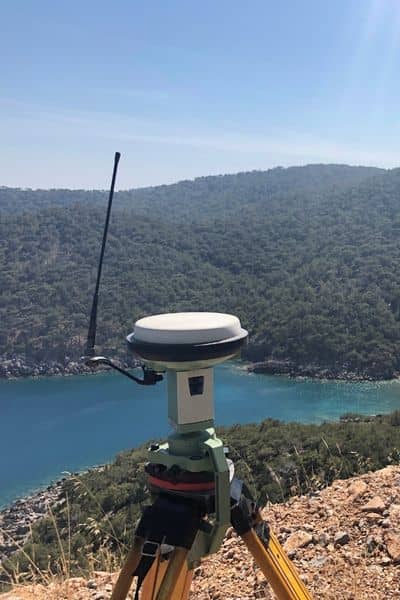 GPS surveying equipment set up on a coastal hill collecting elevation data for an elevation certificate
