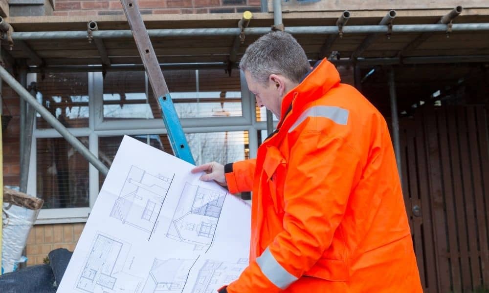 Land surveyor checking blueprints during a property inspection for a loan closing survey