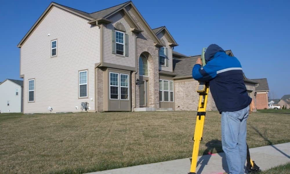 Licensed professional conducting a boundary survey on a residential property to measure lot lines and confirm property boundaries