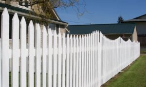 White fence along a residential property line showing a common boundary issue where a house survey can prevent disputes