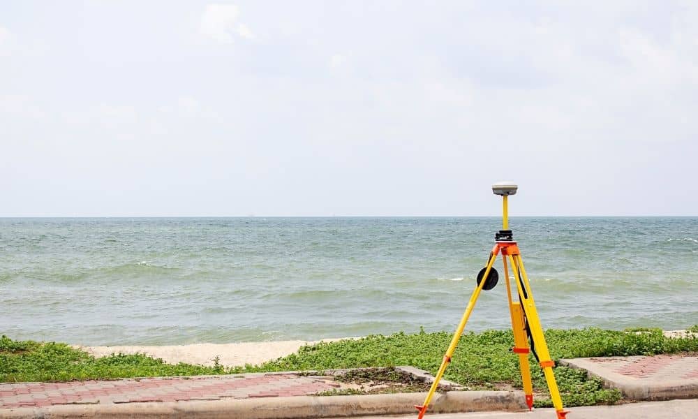 Surveyor measuring coastal elevation levels to assess high-tide flooding risk
