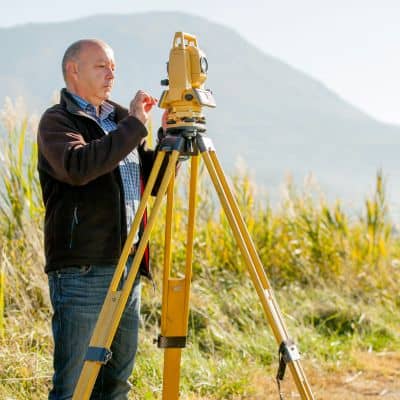 Professional surveyor using total station - ALTA SURVEY Miami Professional surveyor using a total station to verify land survey property boundaries on site