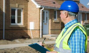 Property verification clipboard surveyor - ALTA SURVEY Miami Professional wearing a hard hat and safety vest holding a clipboard while inspecting a residential property, illustrating verification before closing with an ALTA survey