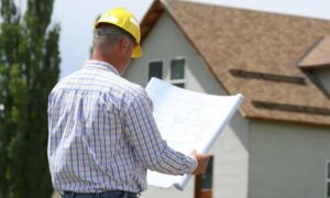 Surveyor reviewing property plans 1 - ALTA SURVEY Miami Licensed surveyor reviewing property plans in front of a home before starting a project